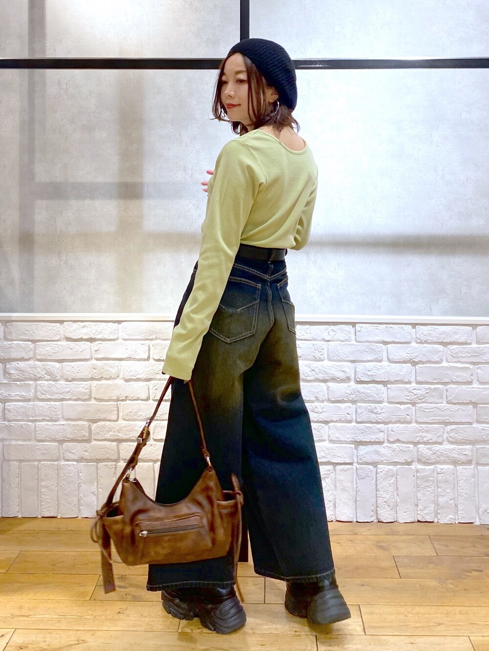 イエロー系のTシャツ/カットソー、ブラウン系のショルダーバッグ、ブルー系のデニムパンツを着用したレディースの冬コーディネートの4枚目の写真