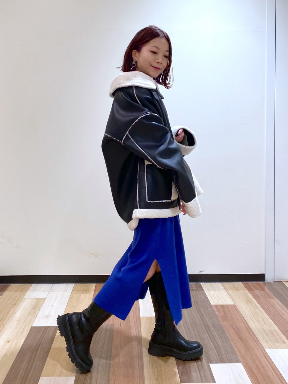 ブラック系のブルゾン、ブラック系のブーツ、ブルー系のワンピースを着用したレディースの冬コーディネートの3枚目の写真
