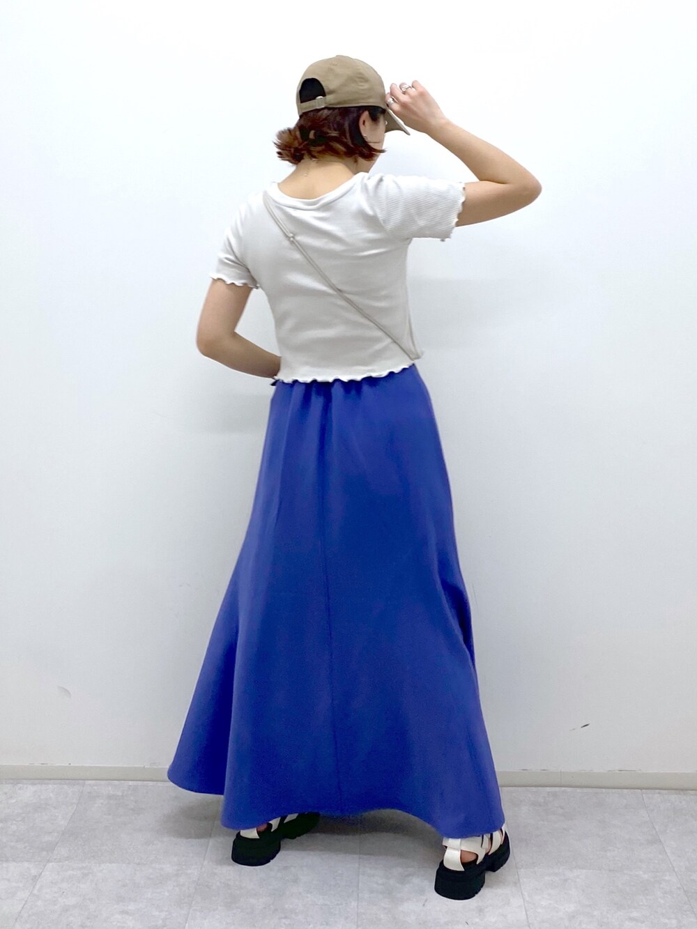 グレー系のトップス、ブルー系のスカート、ベージュ系のショルダーバッグを着用したレディースの夏コーディネートの3枚目の写真