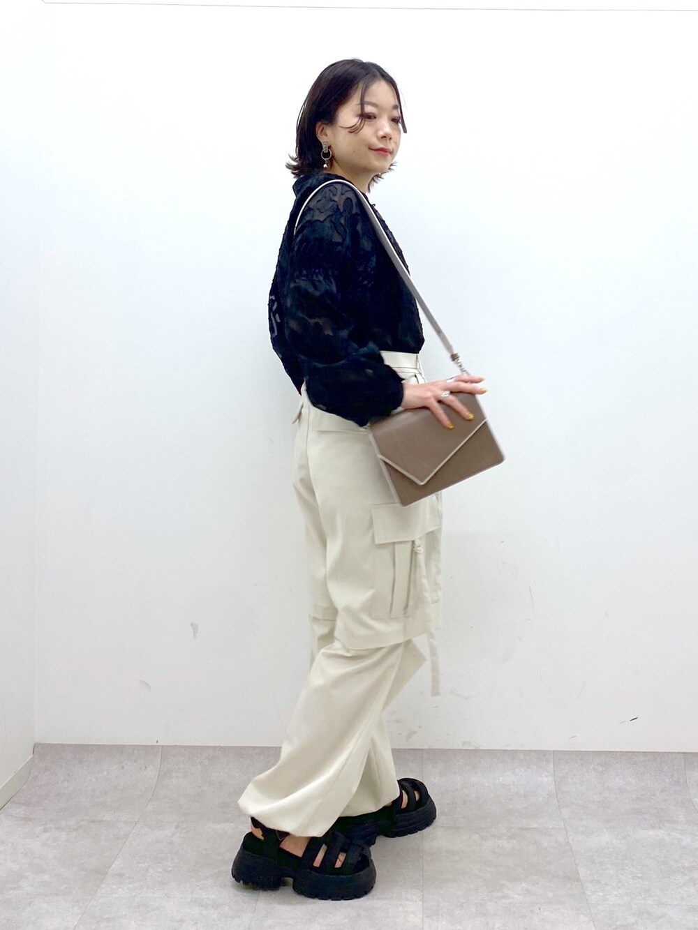 グレー系のパンツ、ブラック系のサンダル、ブラウン系のショルダーバッグを着用したレディースの春コーディネートの2枚目の写真