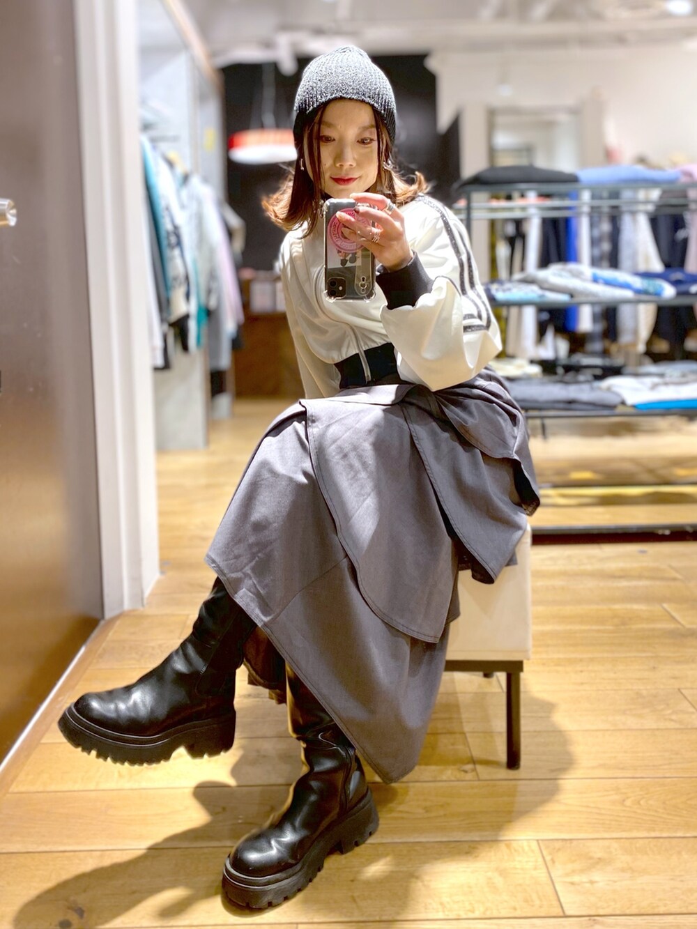 グレー系のスカート、ホワイト系のジャージ、ブラック系のブーツを着用したレディースの冬コーディネートの6枚目の写真