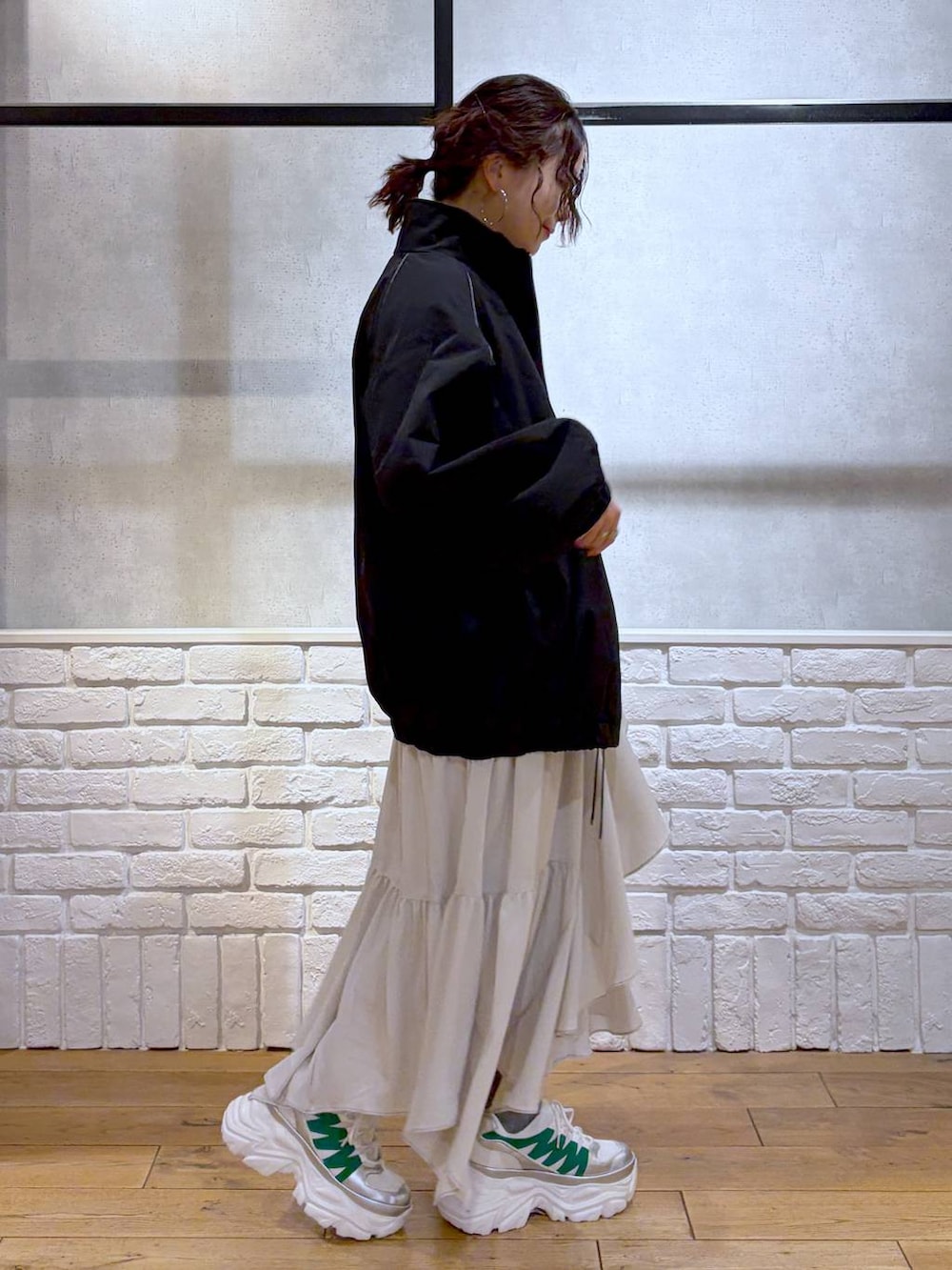 ホワイト系のスニーカー、ベージュ系のスカート、ブラック系のナイロンジャケットを着用したレディースの冬コーディネートの7枚目の写真
