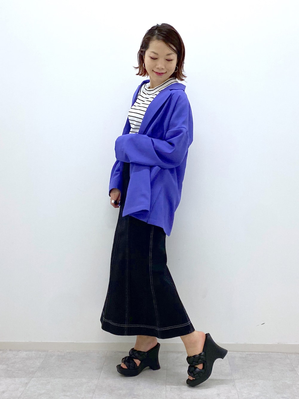ブラック系のデニムスカート、ブラック系のサンダル、パープル系のテーラードジャケットを着用したレディースの春コーディネートの4枚目の写真