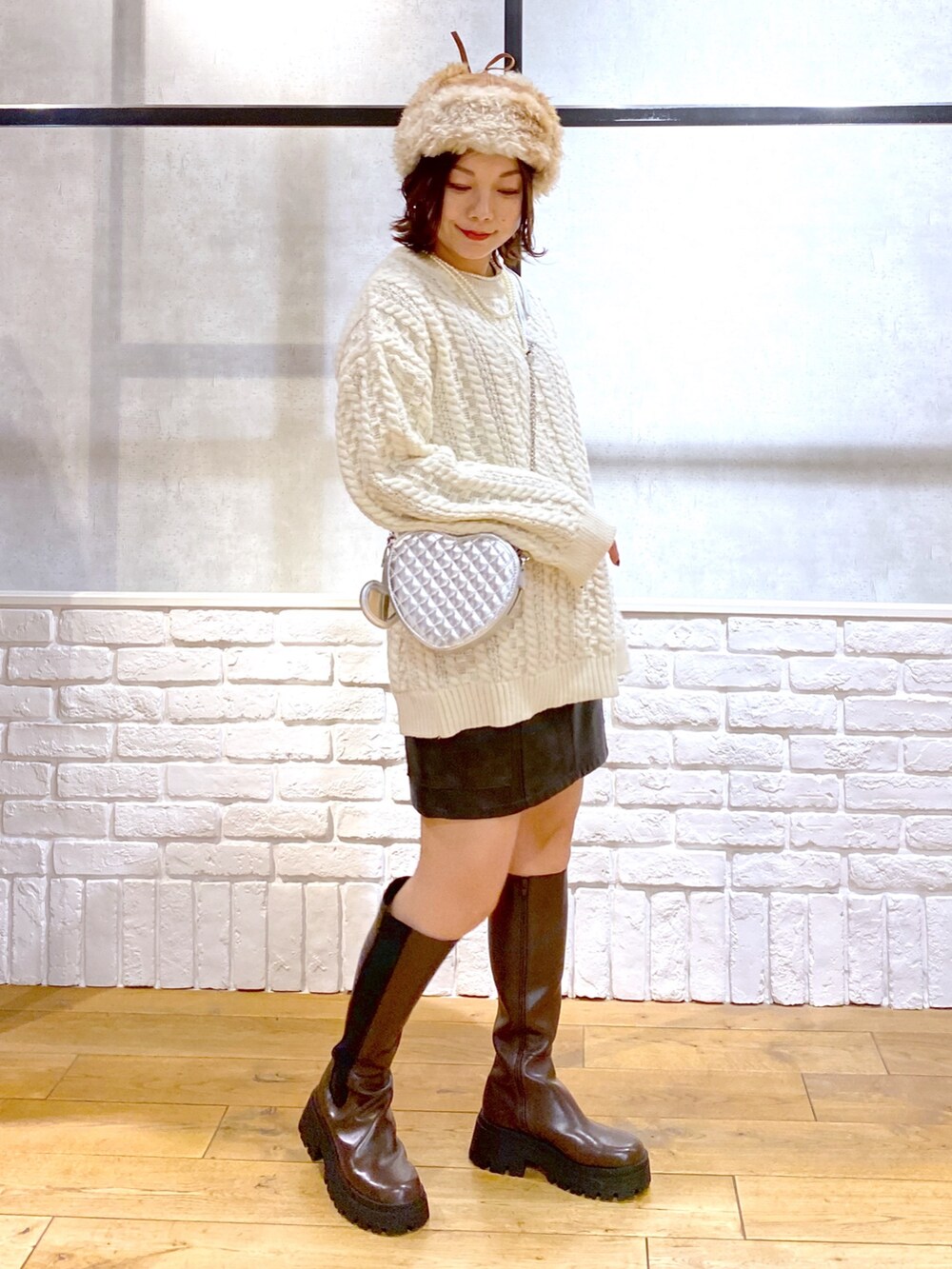 ホワイト系のニット/セーター、ブラック系のスカート、ブラウン系のブーツを着用したレディースの冬コーディネートの8枚目の写真