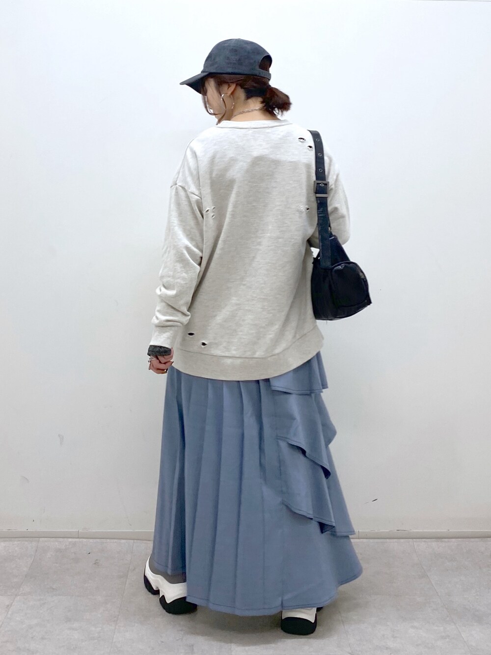 ブラック系のショルダーバッグ、ブルー系のスカート、グレー系のブーツを着用したレディースの秋コーディネートの7枚目の写真