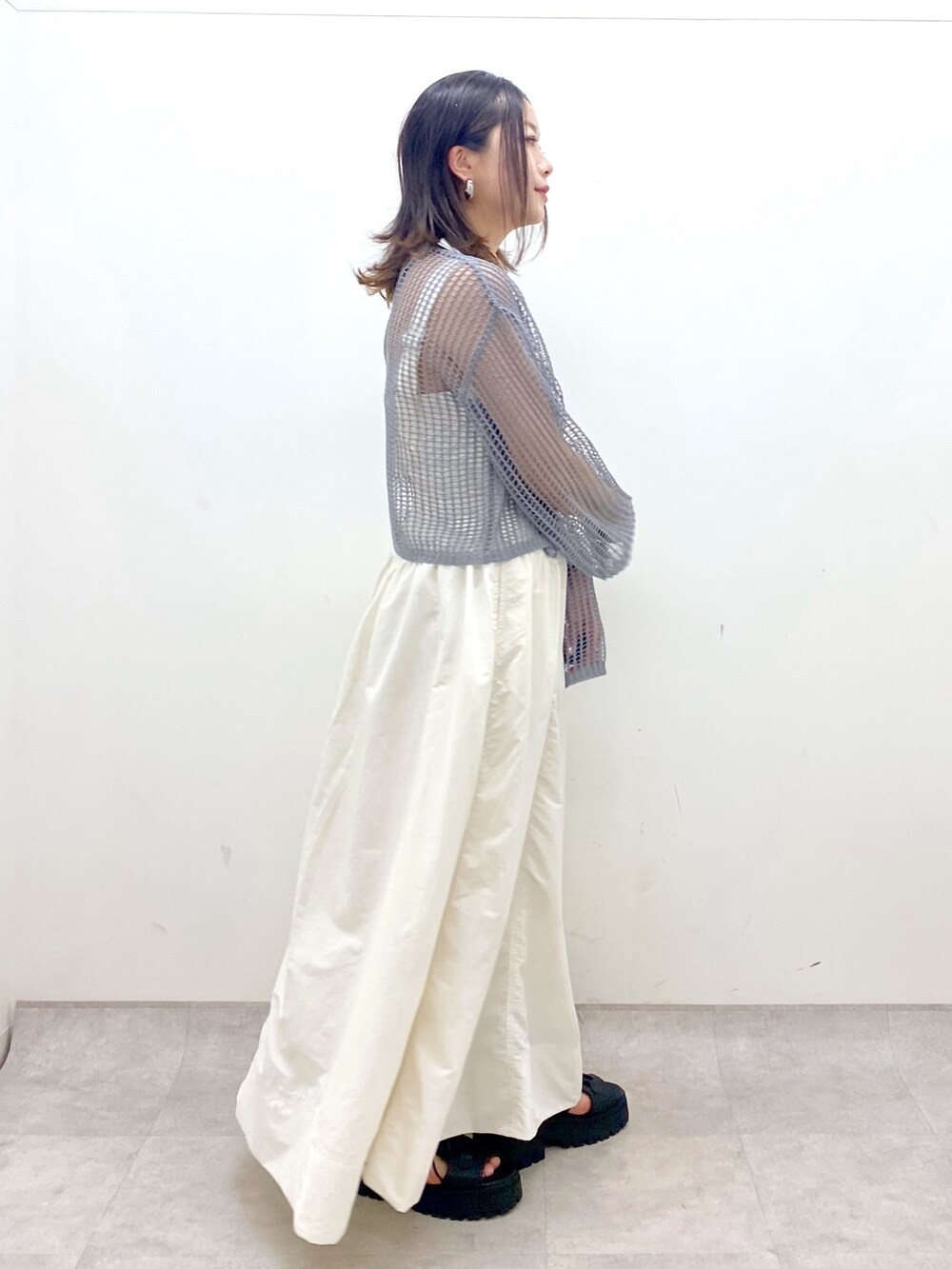 ホワイト系のワンピース、グレー系のカーディガン/ボレロ、ブラック系のサンダルを着用したレディースの春コーディネートの7枚目の写真