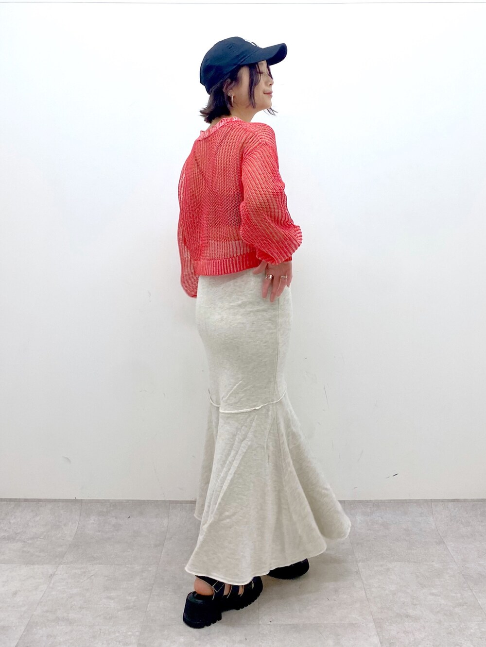 ベージュ系のスカート、レッド系のカーディガン/ボレロ、ブラック系のサンダルを着用したレディースの春コーディネートの2枚目の写真