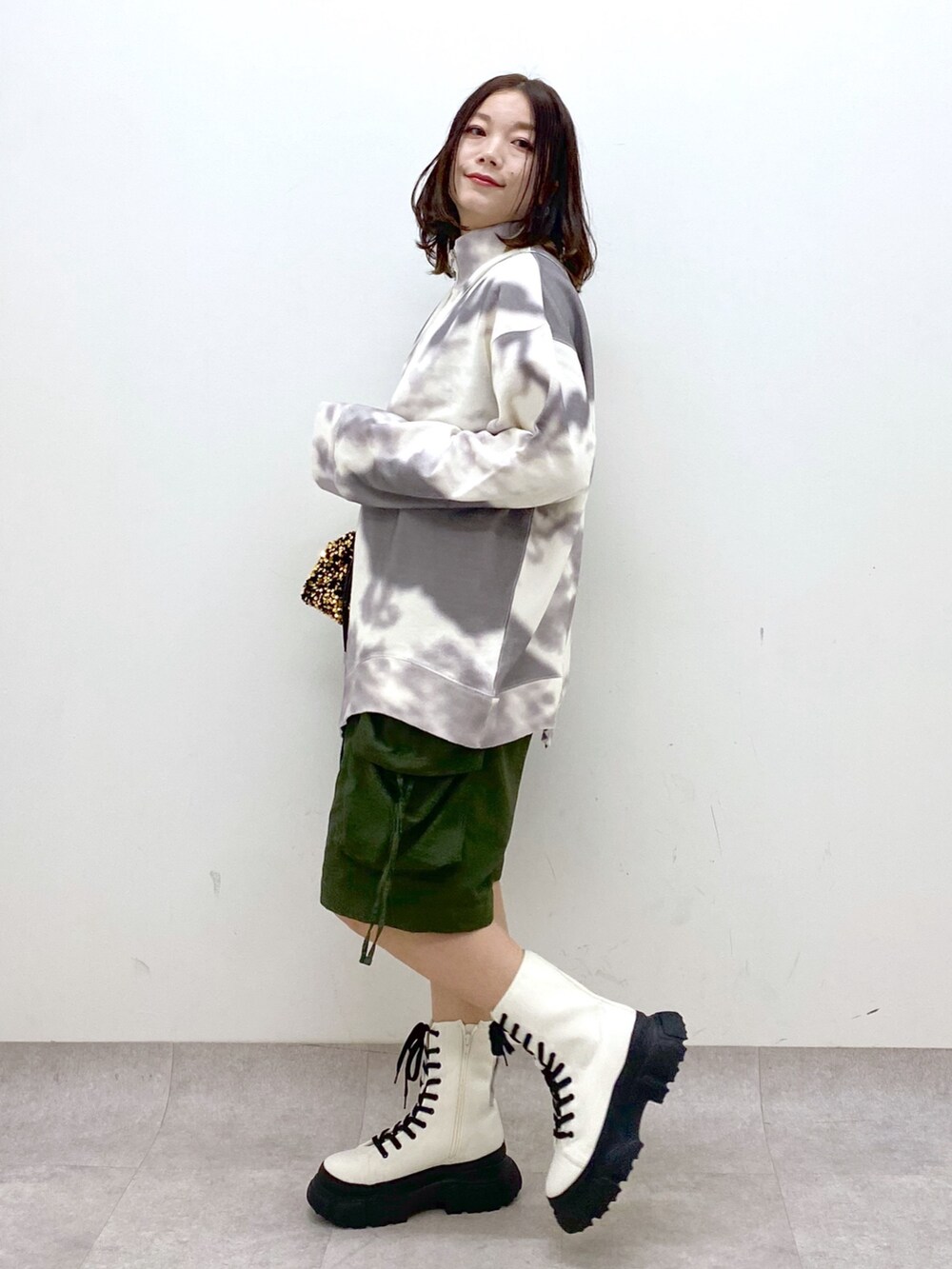 グリーン系のカーゴパンツ、ホワイト系のブーツ、ゴールド系のショルダーバッグを着用したレディースの冬コーディネートの5枚目の写真