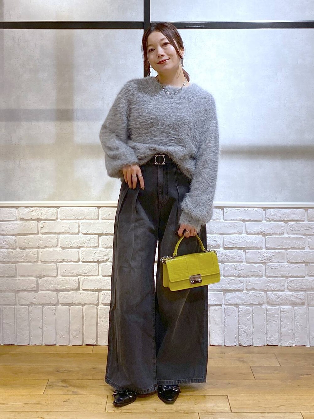ブラック系のデニムパンツ、イエロー系のハンドバッグ、ブラック系のパンプスを着用したレディースの秋コーディネートの9枚目の写真