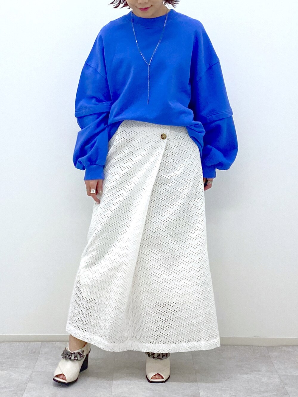 ブルー系のスウェット、ホワイト系のスカート、ホワイト系のパンプスを着用したレディースの冬コーディネートの5枚目の写真