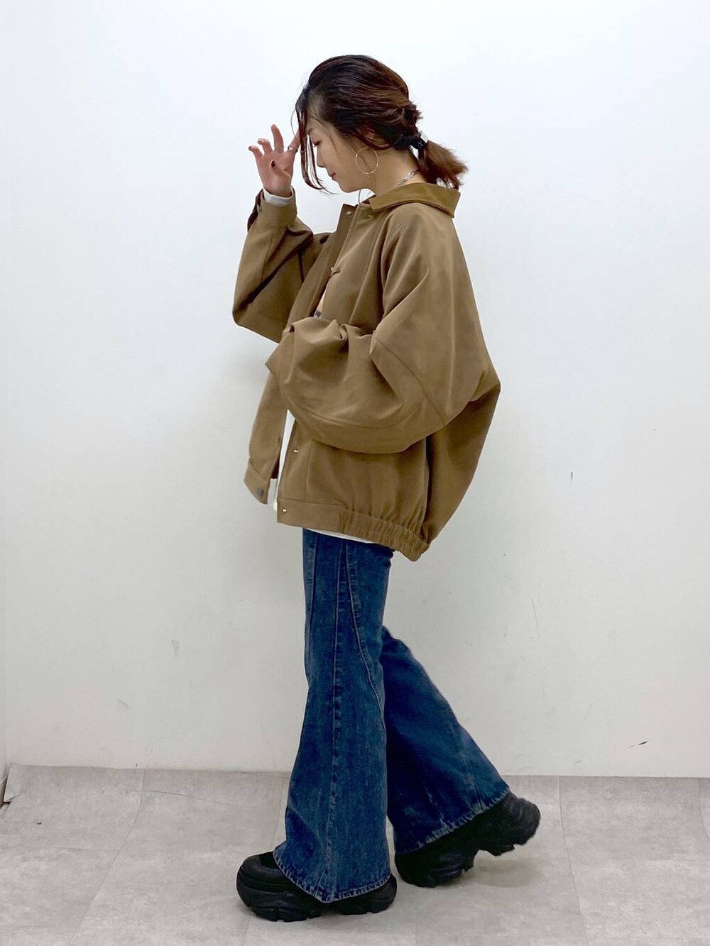 ブラック系のスニーカー、ブルー系のデニムパンツ、ブラウン系のショルダーバッグを着用したレディースの秋コーディネートの7枚目の写真