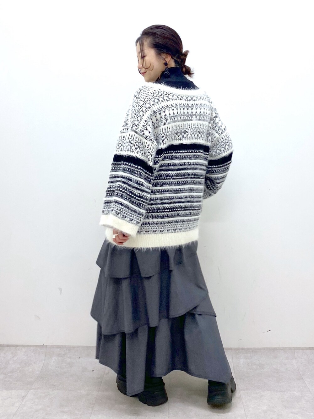 ホワイト系のカーディガン/ボレロ、グレー系のスカート、ブラック系のスニーカーを着用したレディースの冬コーディネートの5枚目の写真