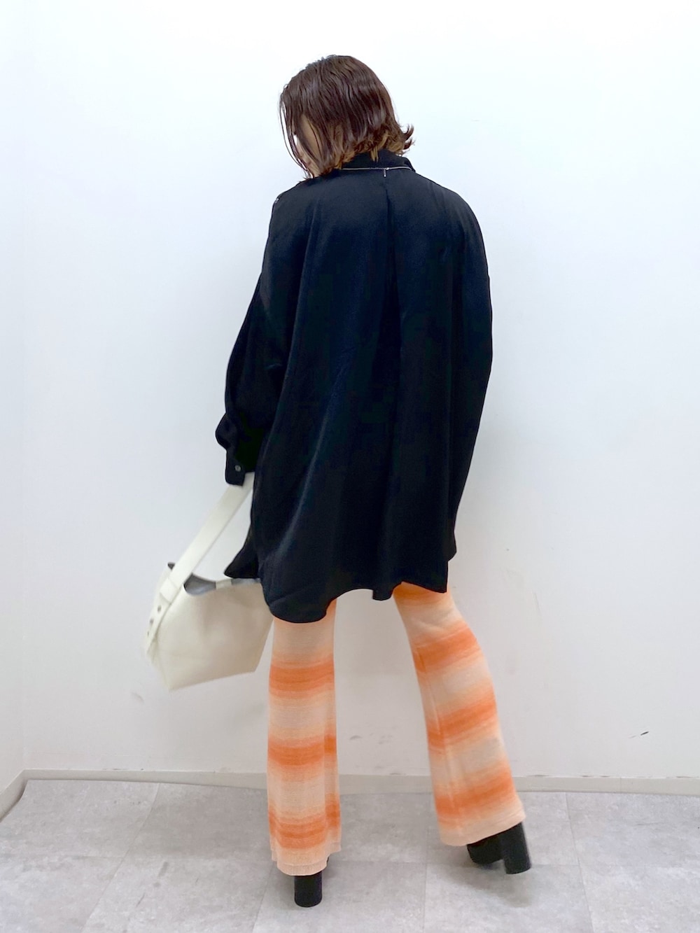 ブラック系のトップス、オレンジ系のその他パンツ、ブラック系のブーツを着用したレディースの夏コーディネートの3枚目の写真