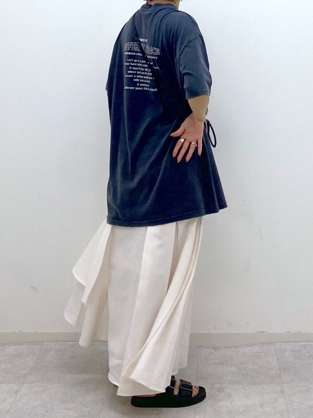 グレー系のTシャツ/カットソー、ホワイト系のスカート、ブラック系のサンダルを着用したレディースの夏コーディネートの4枚目の写真