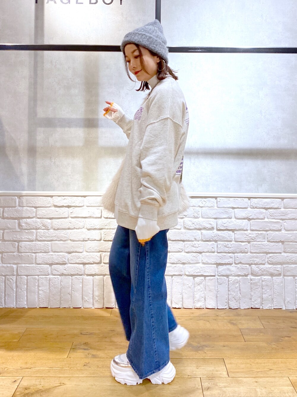 ホワイト系のショルダーバッグ、ブルー系のデニムパンツ、ホワイト系のブーツを着用したレディースの秋コーディネートの8枚目の写真