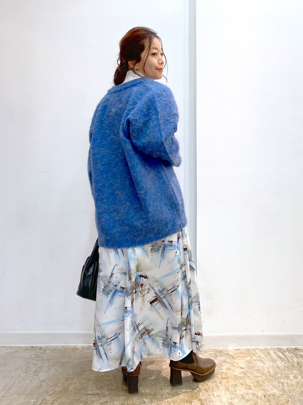 ホワイト系のニット/セーター、ブラック系のハンドバッグ、ブラウン系のブーツを着用したレディースの秋コーディネートの4枚目の写真