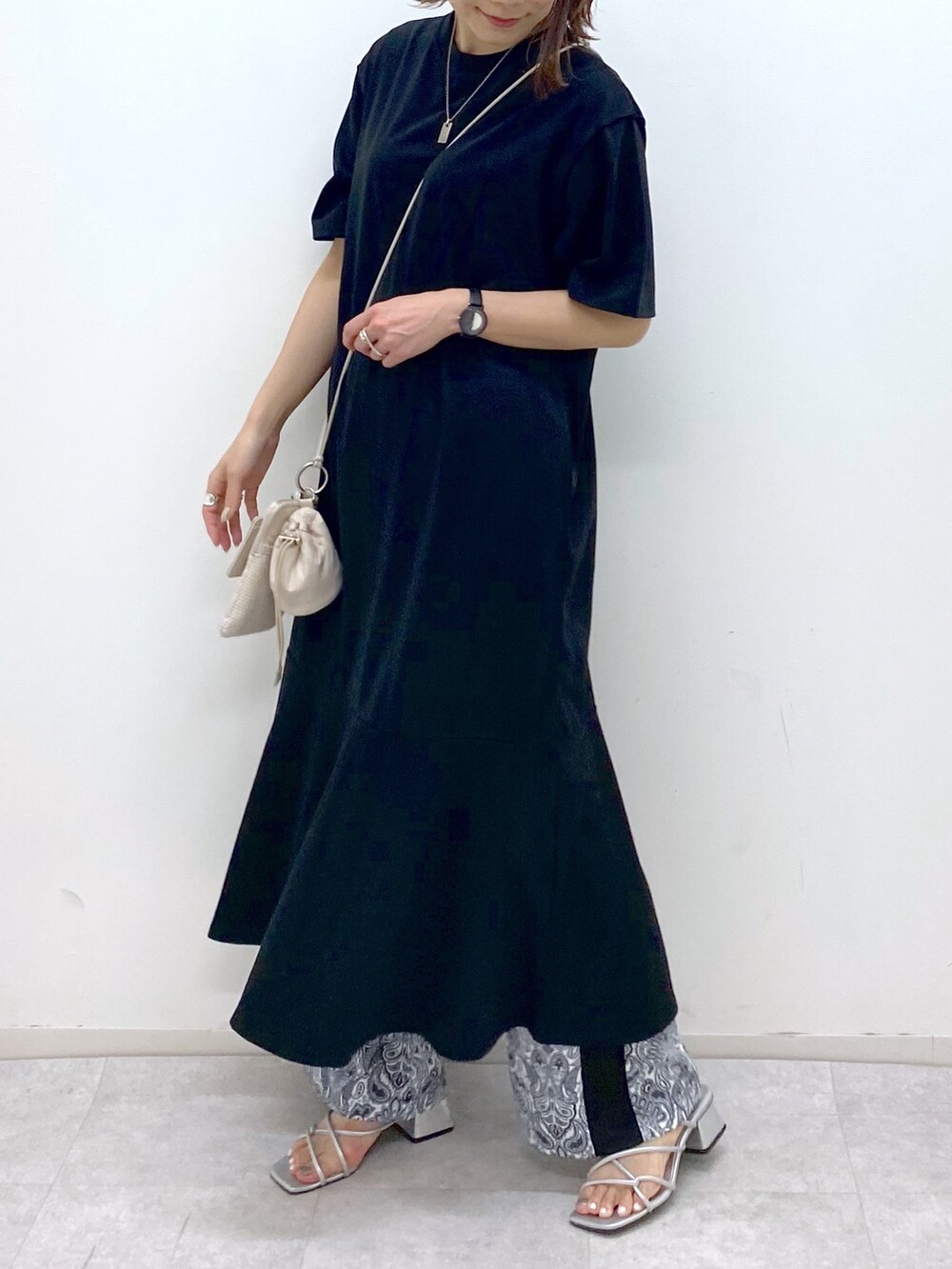 ブラック系のワンピース、ベージュ系のショルダーバッグ、シルバー系のサンダルを着用したレディースの夏コーディネートの4枚目の写真