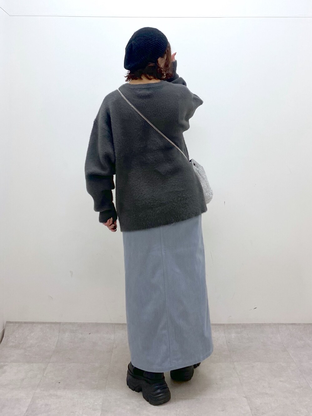 グレー系のニット/セーター、ブルー系のスカート、ブラック系のブーツを着用したレディースの秋コーディネートの6枚目の写真