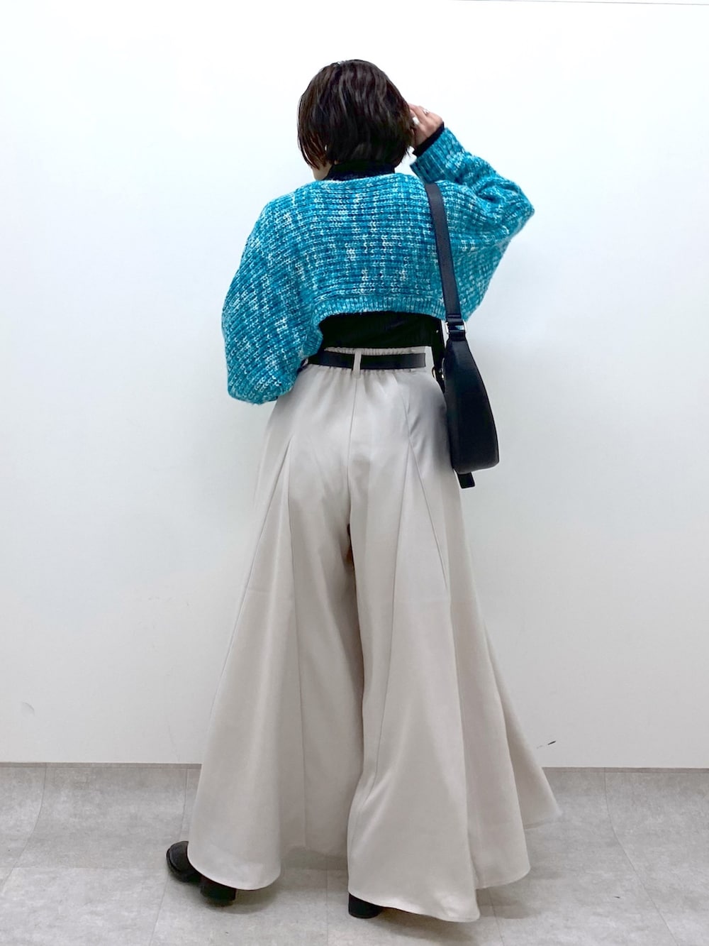 ベージュ系のスラックス、ブラック系のトップス、ブルー系のカーディガン/ボレロを着用したレディースの冬コーディネートの2枚目の写真