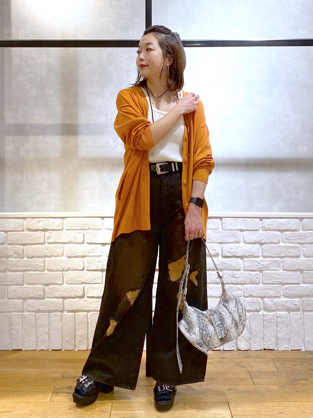 ホワイト系のタンクトップ、オレンジ系のカーディガン/ボレロ、ブラック系のデニムパンツを着用したレディースの春コーディネートの4枚目の写真
