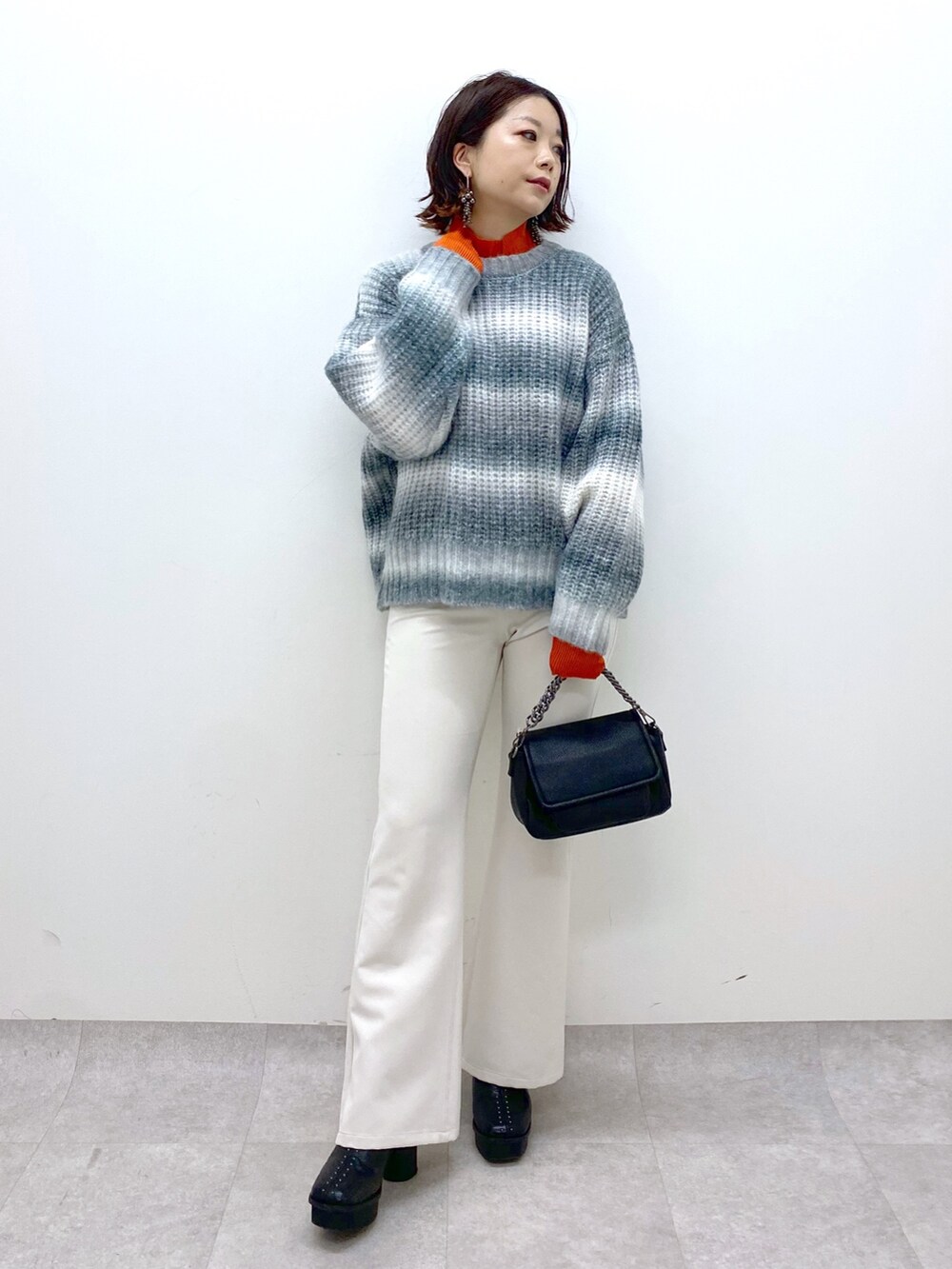 ブラック系のトップス、オレンジ系のトップス、ブラック系のバッグを着用したレディースの秋コーディネートの2枚目の写真