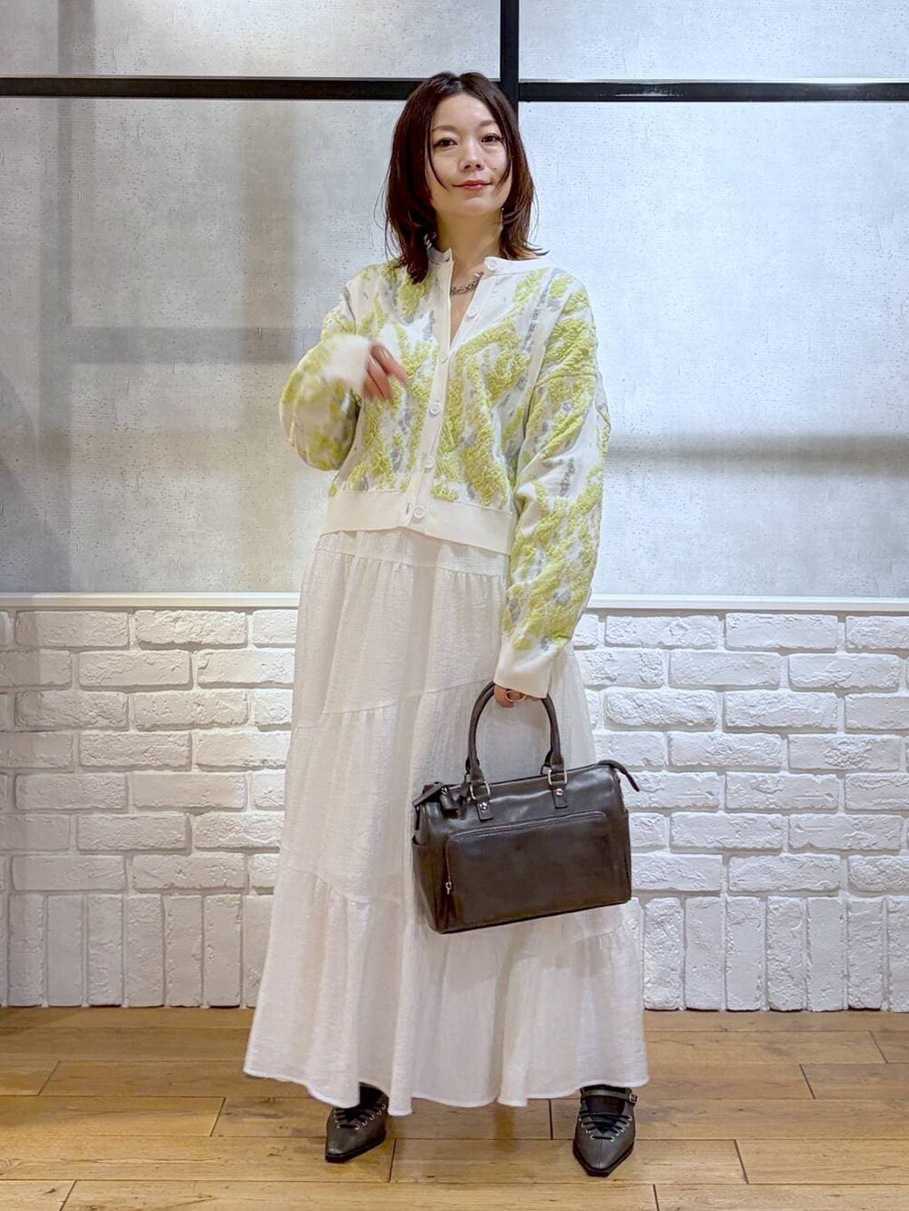 グレー系のショルダーバッグ、ブラウン系のサンダル、ホワイト系のスカートを着用したレディースの冬コーディネートの9枚目の写真