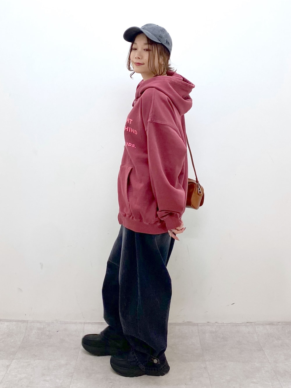 レッド系のスウェット、ブラック系のデニムパンツ、ブラック系のローファーを着用したレディースの冬コーディネートの5枚目の写真