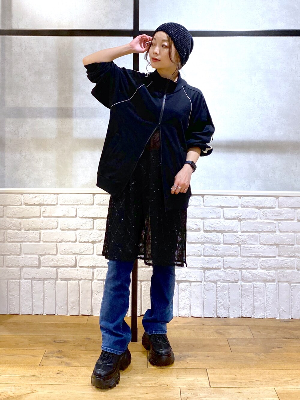 ブラック系のスウェット、ブラック系のワンピース、ブルー系のデニムパンツを着用したレディースの春コーディネートの4枚目の写真