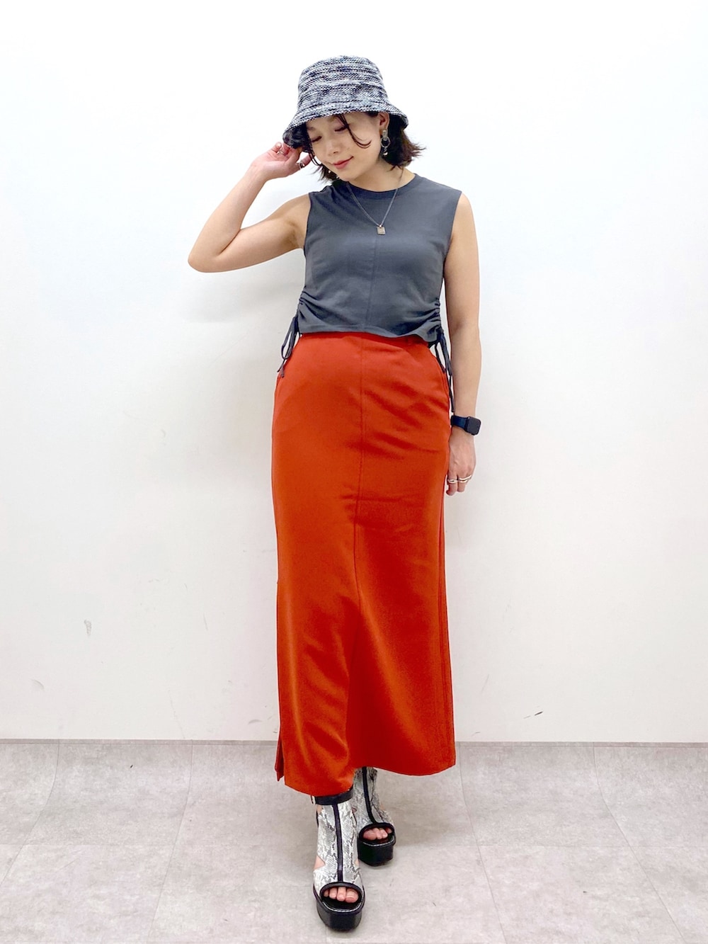 ホワイト系のサンダル、オレンジ系のスカート、グレー系のTシャツ/カットソーを着用したレディースの夏コーディネートの2枚目の写真