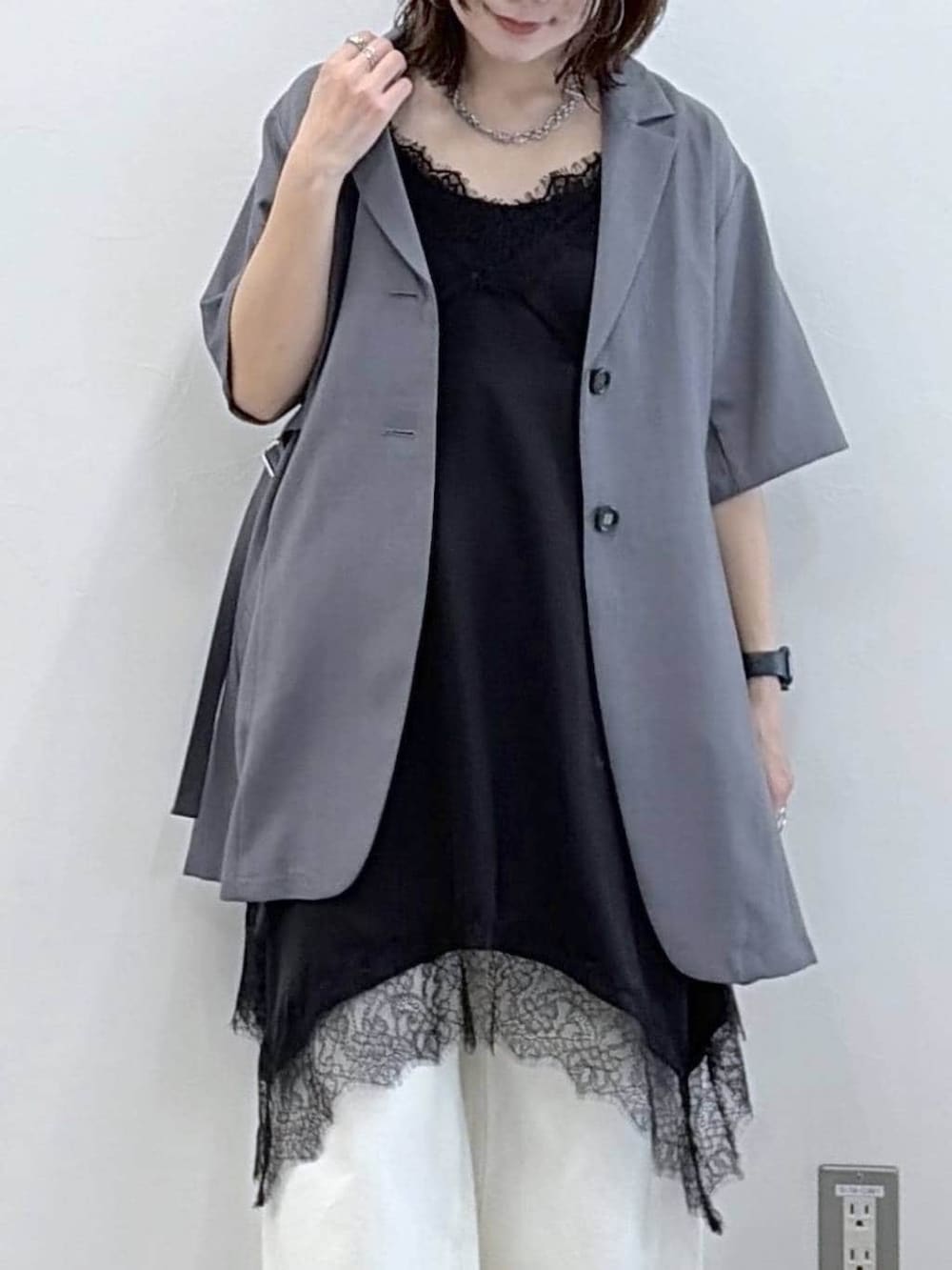 ホワイト系のスラックス、ブラック系のチュニック、ブラック系のサンダルを着用したレディースの春コーディネートの2枚目の写真