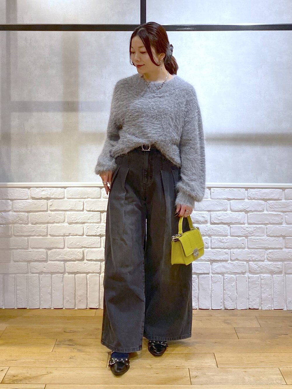 ブラック系のデニムパンツ、イエロー系のハンドバッグ、ブラック系のパンプスを着用したレディースの秋コーディネートの4枚目の写真