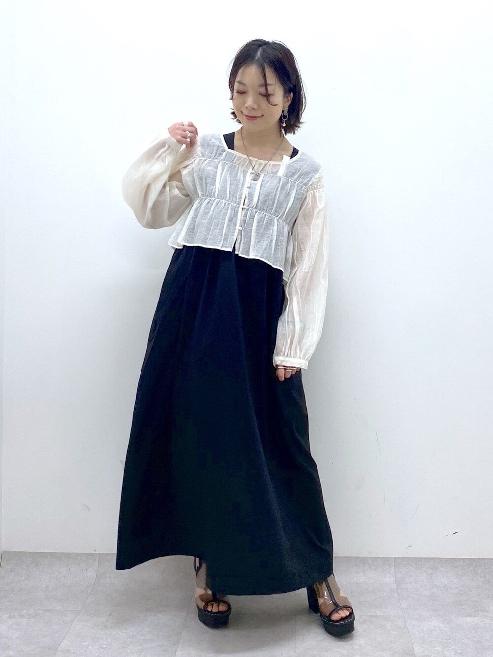 ブラック系のジャンパースカート、ホワイト系のシャツ/ブラウス、その他のサンダルを着用したレディースの夏コーディネートの2枚目の写真