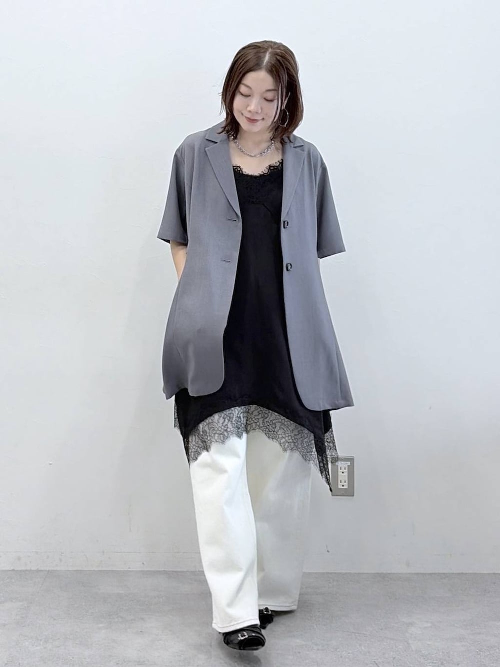 ホワイト系のスラックス、ブラック系のチュニック、ブラック系のサンダルを着用したレディースの春コーディネートの4枚目の写真