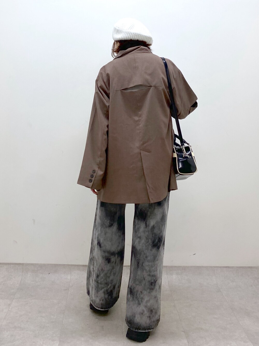 ブラック系のデニムパンツ、ブラック系のスニーカー、ブラウン系のテーラードジャケットを着用したレディースの秋コーディネートの6枚目の写真