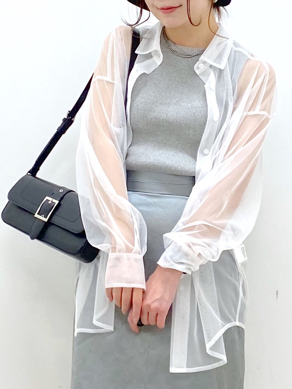 ブルー系のスカート、ブラック系のハンドバッグ、ブラック系のサンダルを着用したレディースの春コーディネートの2枚目の写真