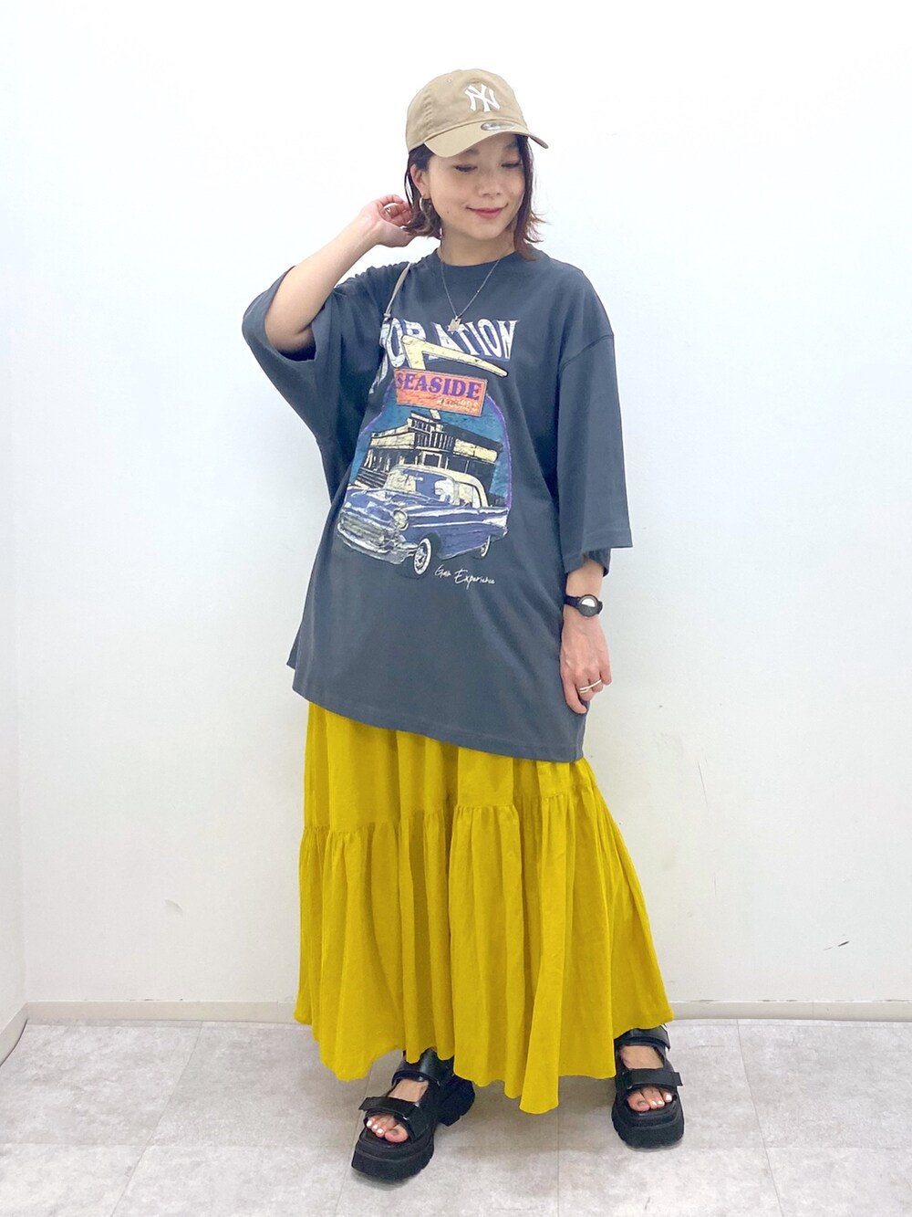 グレー系のTシャツ/カットソー、イエロー系のスカート、ブラック系のサンダルを着用したレディースの夏コーディネートの5枚目の写真