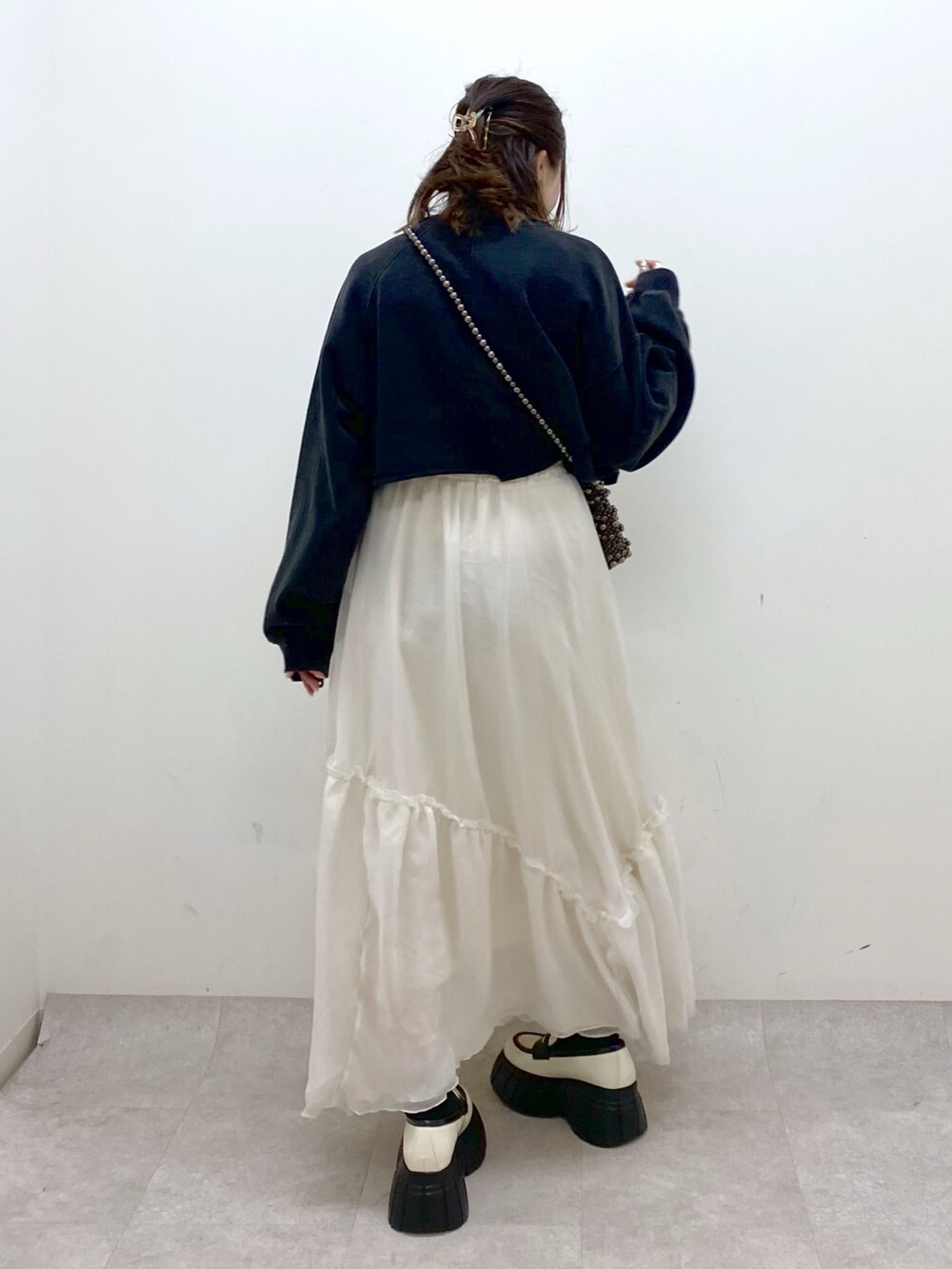 ブラック系のスウェット、ブラック系のショルダーバッグ、ホワイト系のスカートを着用したレディースの冬コーディネートの6枚目の写真