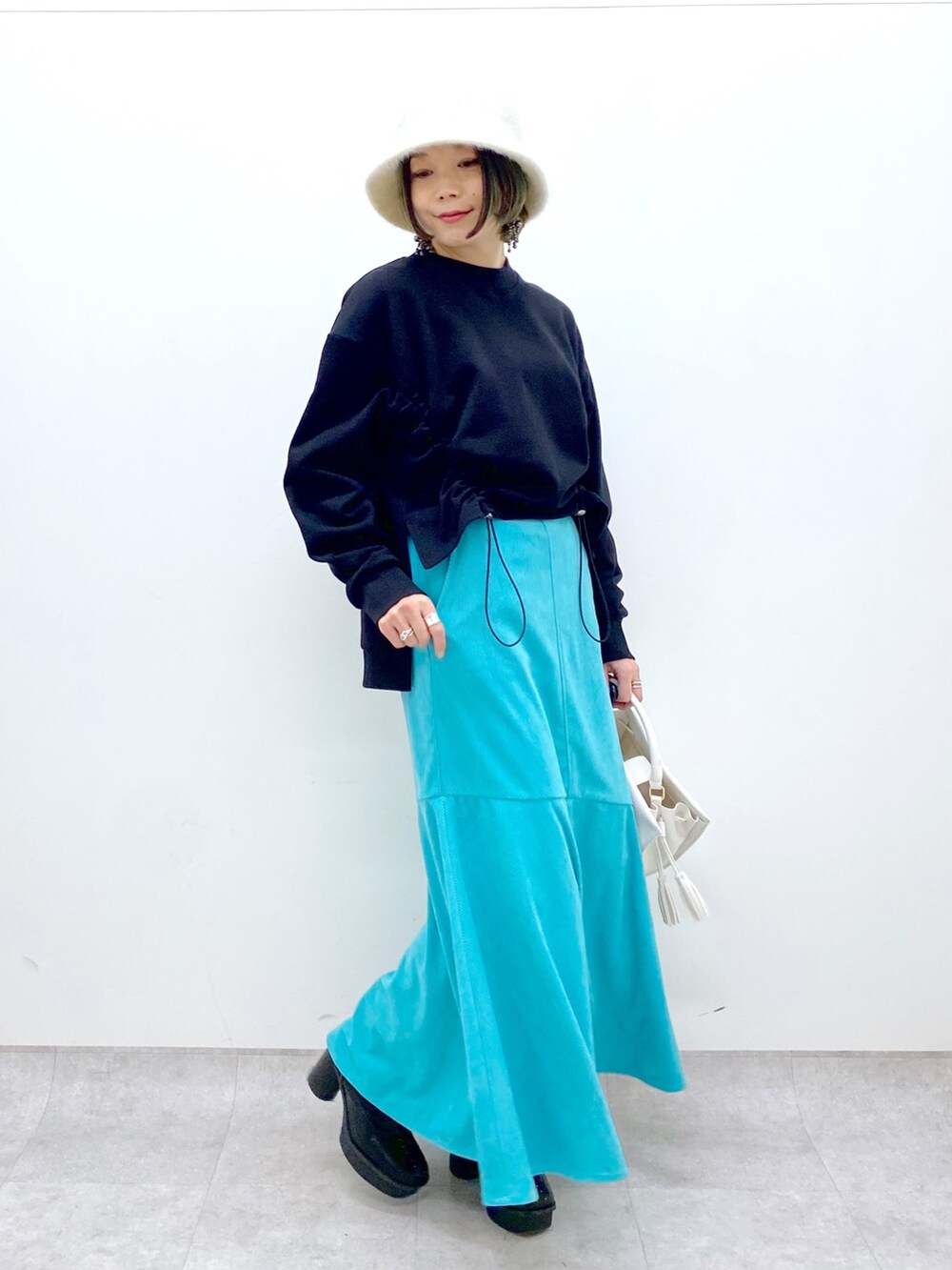 ホワイト系のショルダーバッグ、ブラック系のブーツ、ブラック系のトップスを着用したレディースの冬コーディネートの2枚目の写真