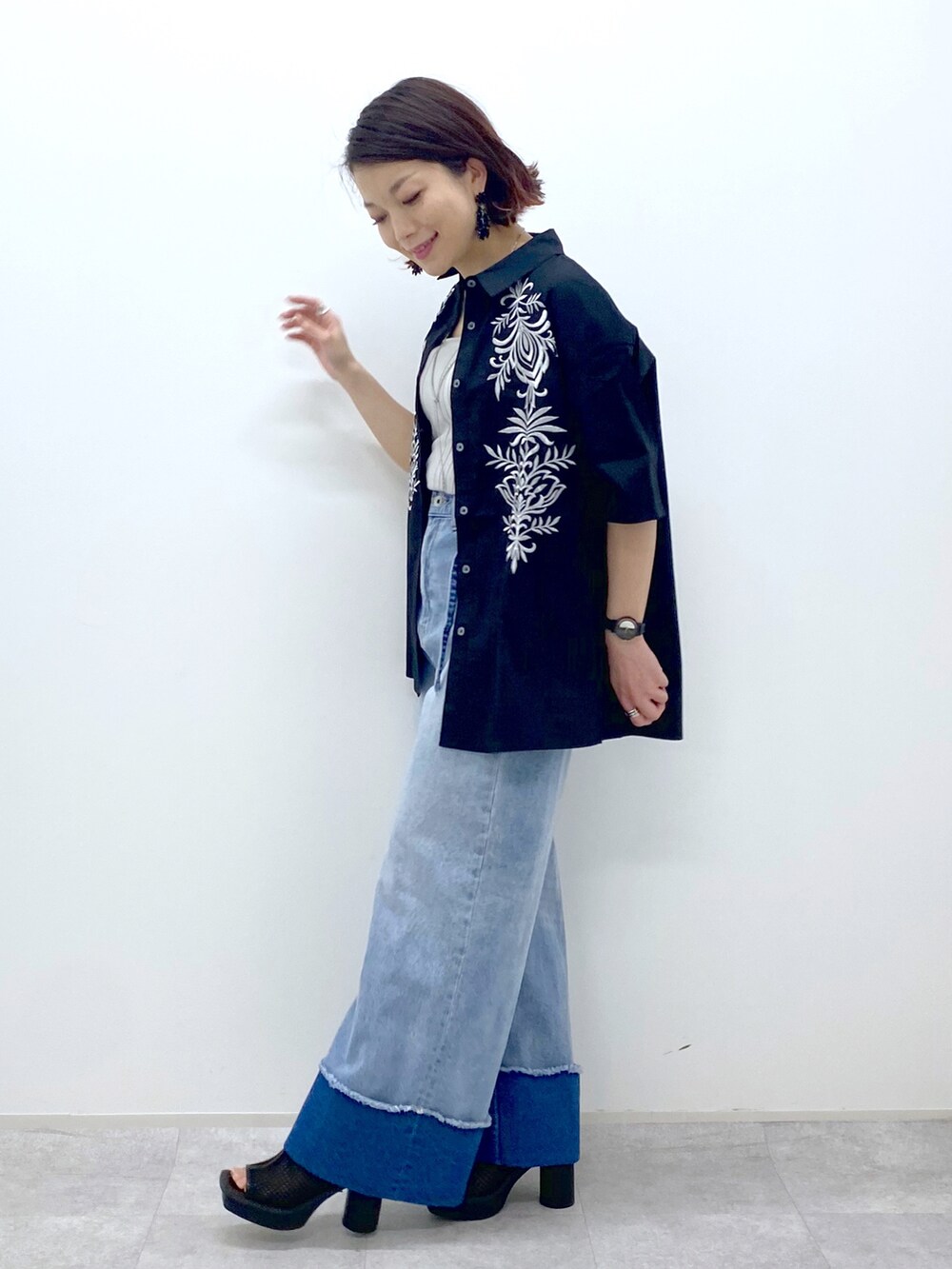 ブルー系のデニムパンツ、ブラック系のシャツ/ブラウス、ベージュ系のタンクトップを着用したレディースの春コーディネートの3枚目の写真