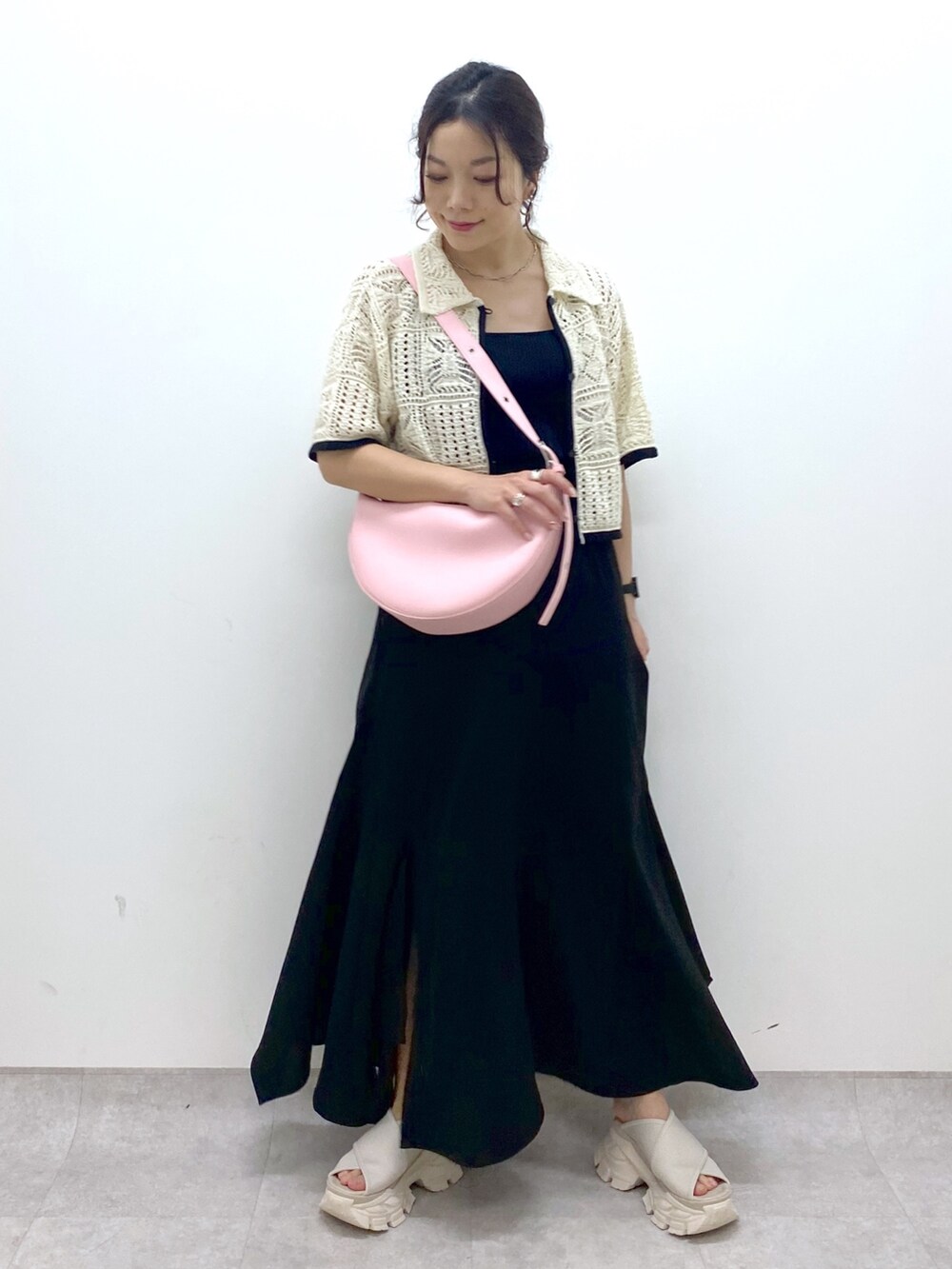 ブラック系のスカート、ホワイト系のカーディガン/ボレロ、ピンク系のショルダーバッグを着用したレディースの夏コーディネートの6枚目の写真