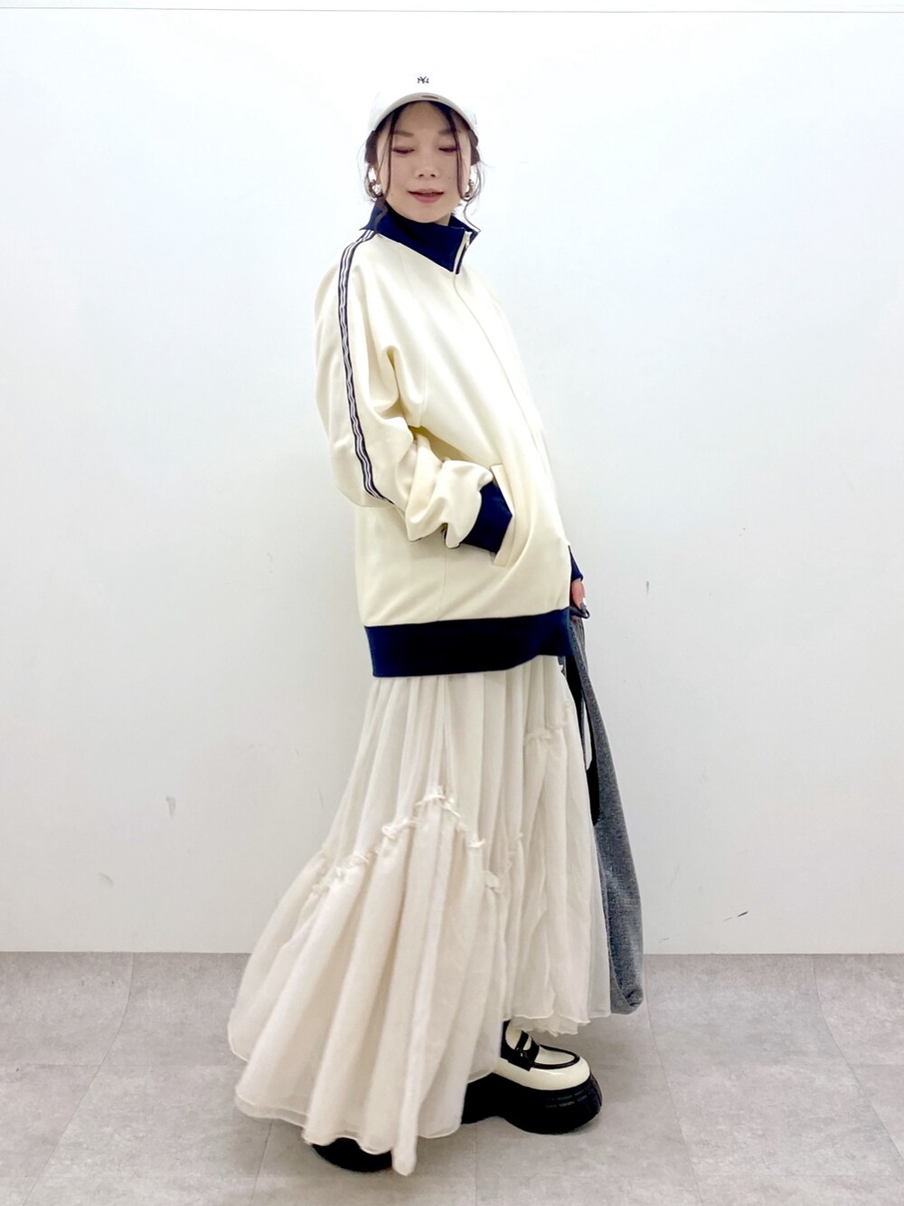 ホワイト系のセットアップ、ブラック系のトートバッグ、ホワイト系のスカートを着用したレディースの冬コーディネートの4枚目の写真