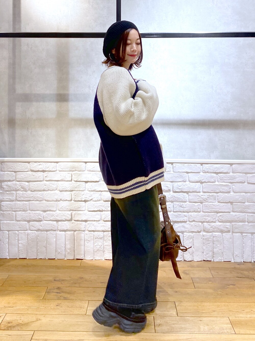 イエロー系のTシャツ/カットソー、ブラウン系のショルダーバッグ、ブルー系のデニムパンツを着用したレディースの冬コーディネートの8枚目の写真