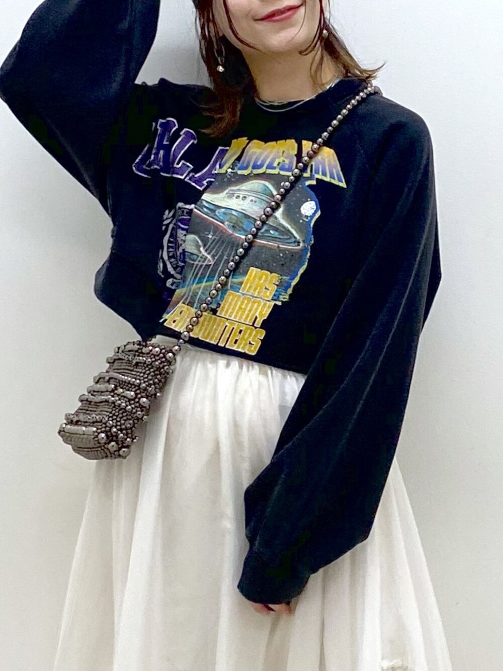 ブラック系のスウェット、ブラック系のショルダーバッグ、ホワイト系のスカートを着用したレディースの冬コーディネートの2枚目の写真