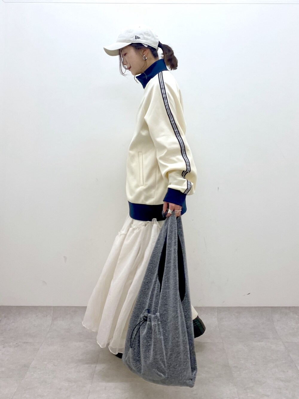 ホワイト系のセットアップ、ブラック系のトートバッグ、ホワイト系のスカートを着用したレディースの冬コーディネートの6枚目の写真