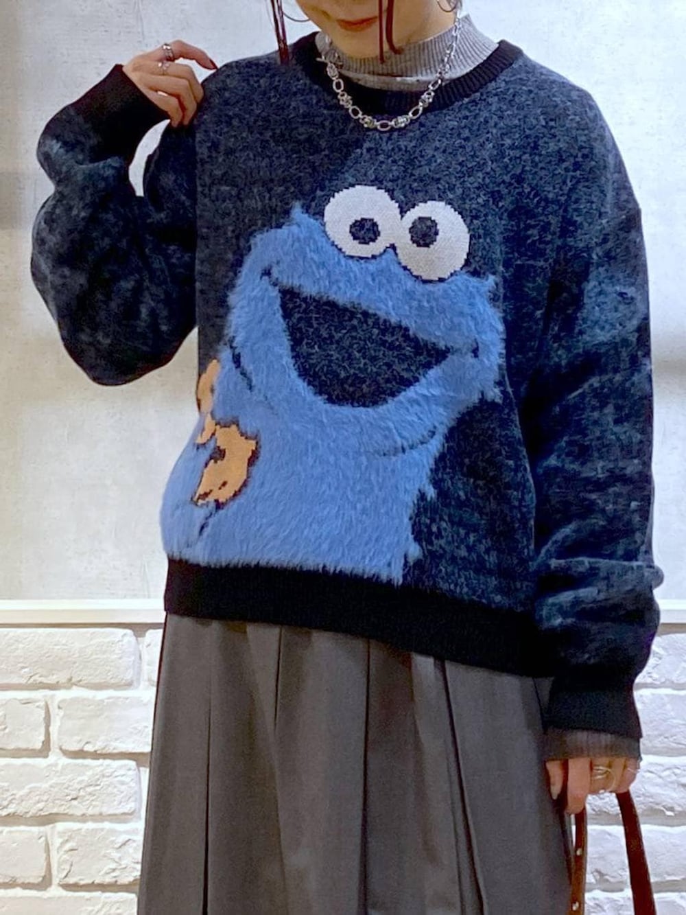 ブラック系のローファー、グレー系のスカート、ブラウン系のショルダーバッグを着用したレディースの冬コーディネートの2枚目の写真