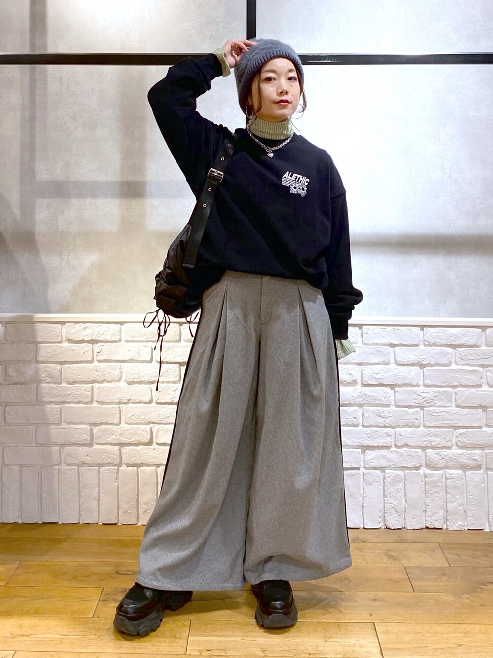 ブラック系のスウェット、グリーン系のショルダーバッグ、ブラック系のスラックスを着用したレディースの秋コーディネートの4枚目の写真