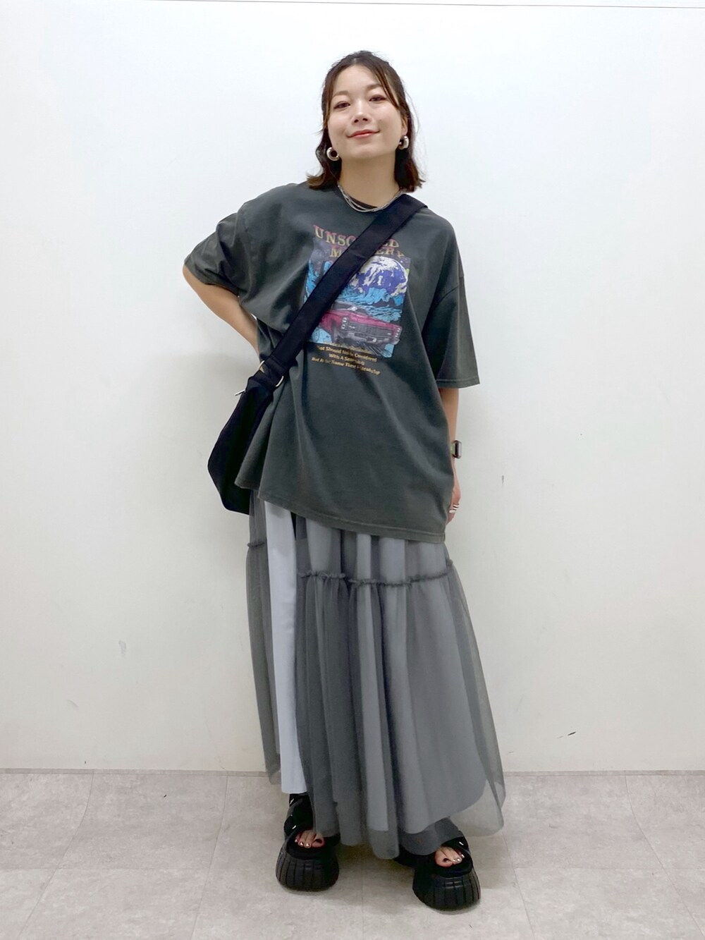 グレー系のTシャツ/カットソー、グレー系のスカート、ブラック系のスニーカーを着用したレディースの夏コーディネートの7枚目の写真