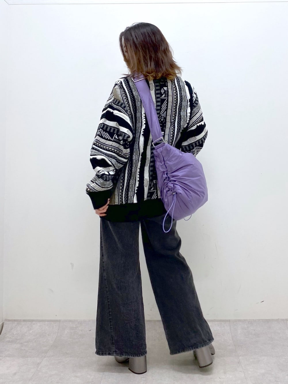 ブラック系のニット/セーター、ブラック系のデニムパンツ、パープル系のショルダーバッグを着用したレディースの秋コーディネートの5枚目の写真