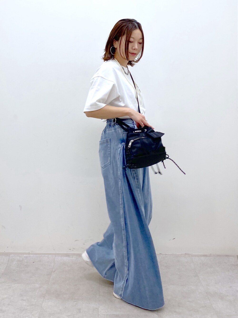 ホワイト系のTシャツ/カットソー、ブラック系のボディバッグ/ウエストポーチ、ブルー系のデニムパンツを着用したレディースの春コーディネートの5枚目の写真