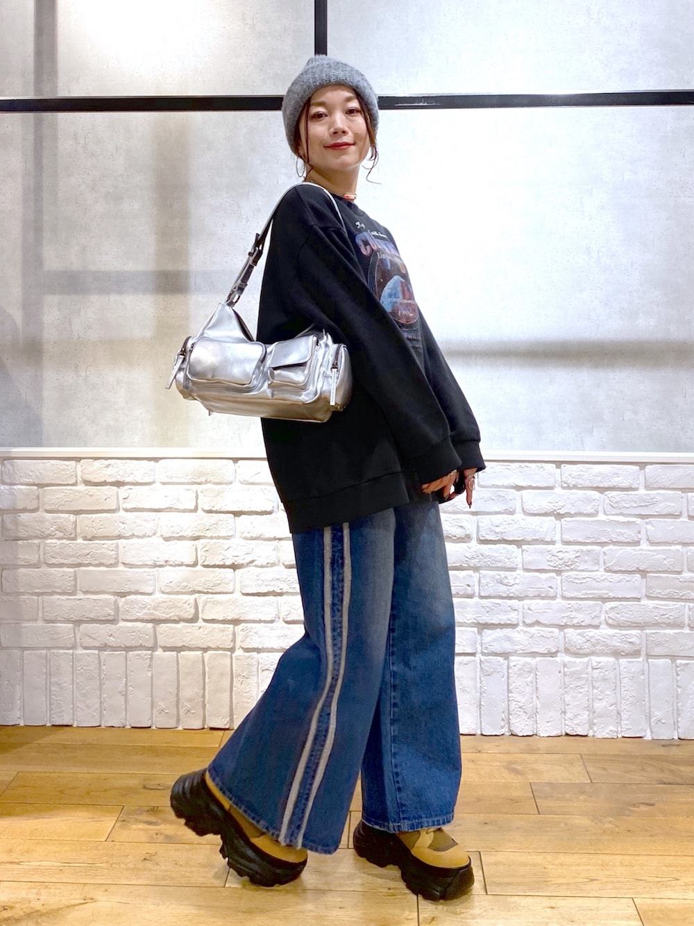 グレー系のスウェット、ブルー系のデニムパンツ、ブラウン系のブーツを着用したレディースの冬コーディネートの5枚目の写真